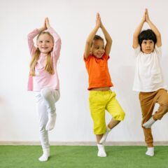 Three diverse children practicing yoga indoors, showcasing joy and balance.